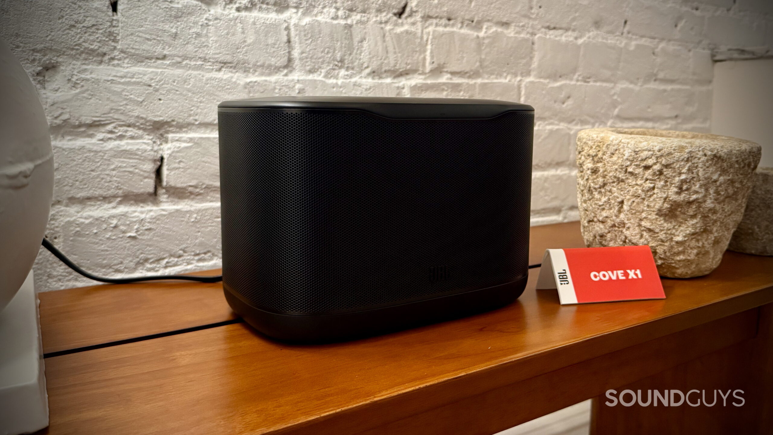 JBL Cove Series - 3 Black JBL Cove X1 Wi-Fi speaker sitting on a wooden table.