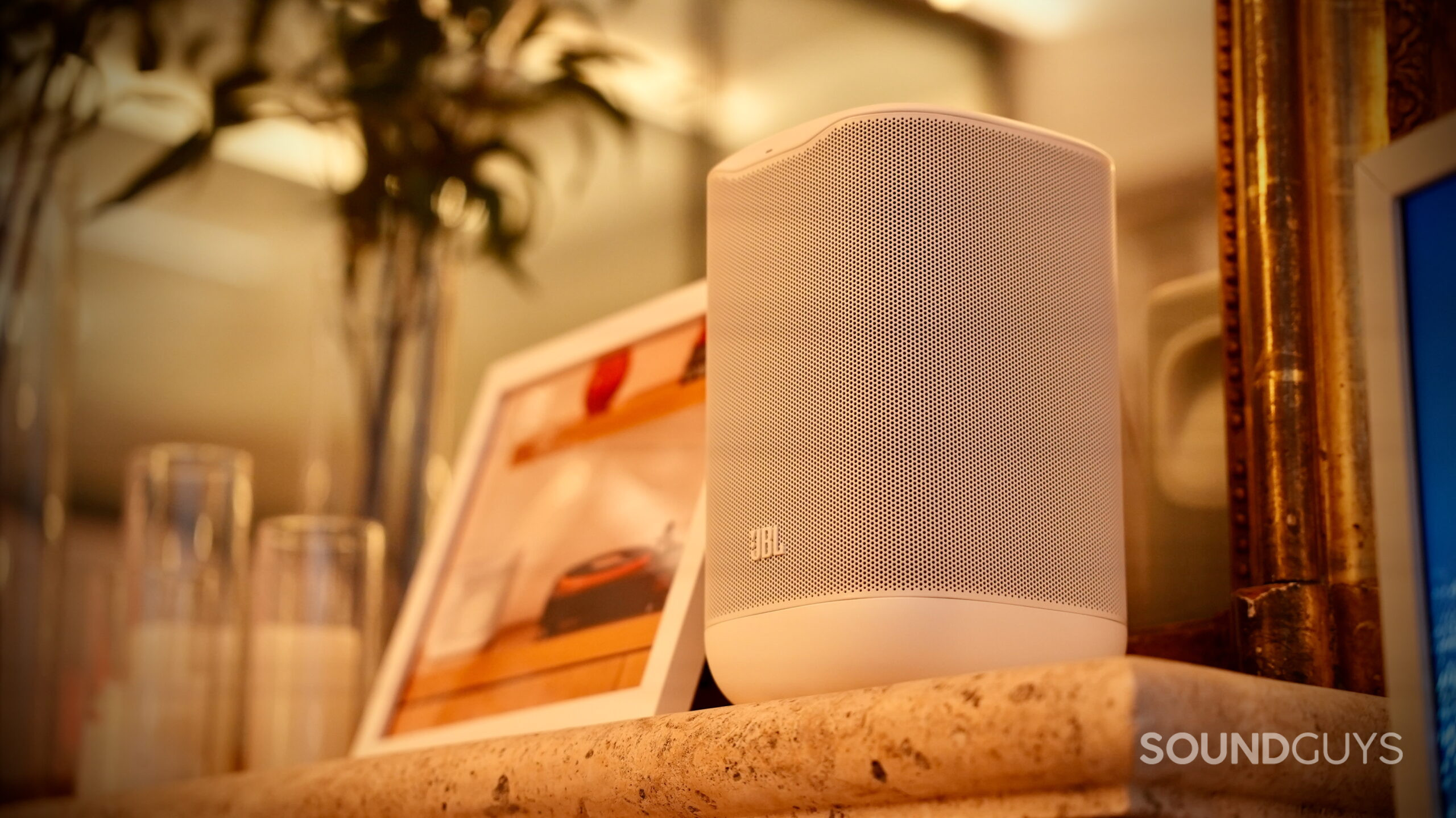 White JBL Cove P1 Wi-Fi speaker displayed on a shelf.