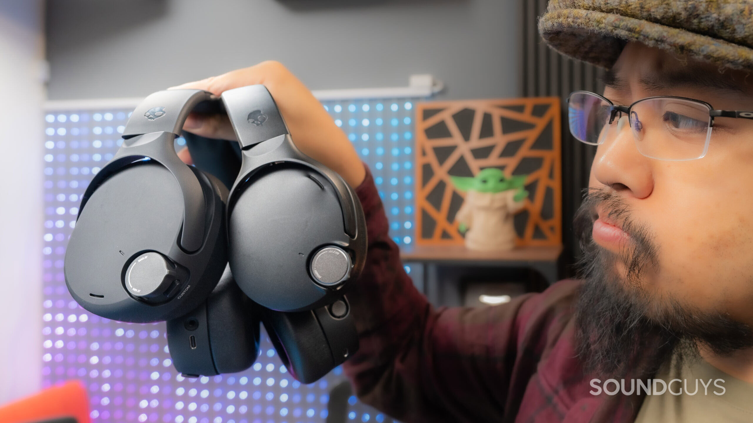 A man holding the SkullCandy Crusher 1080 ANC vs Crusher 720 held side by side with questioning glance