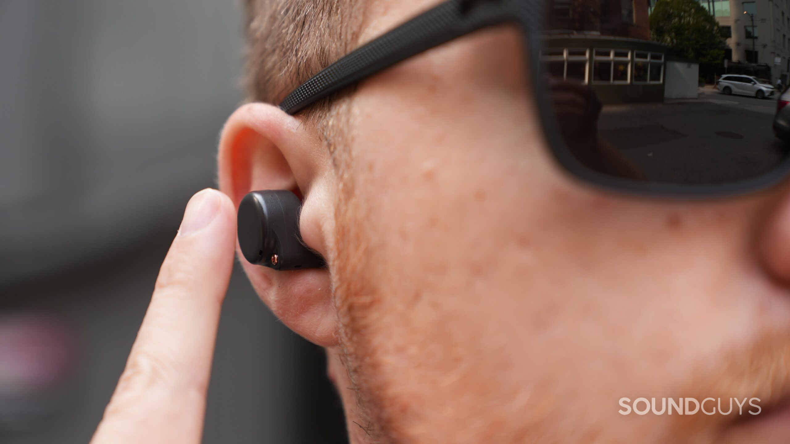 Close-up of a man tapping the touch controls on a ROSESELSA Ceramics Ultra earbud.
