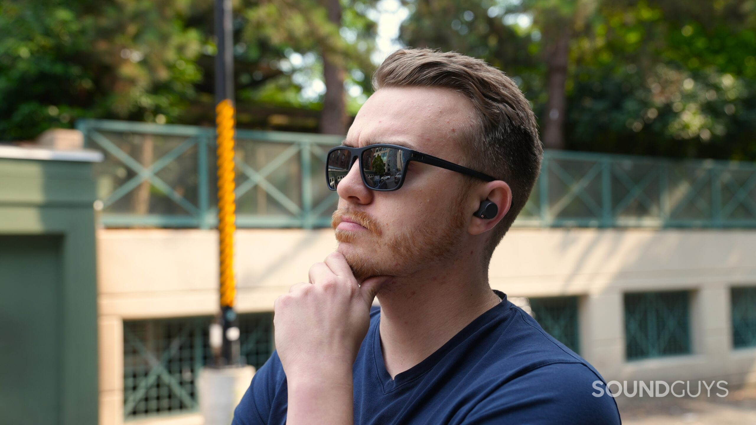 A man wearing sunglasses listens to the ROSESELSA Ceramics Ultra earbuds outdoors