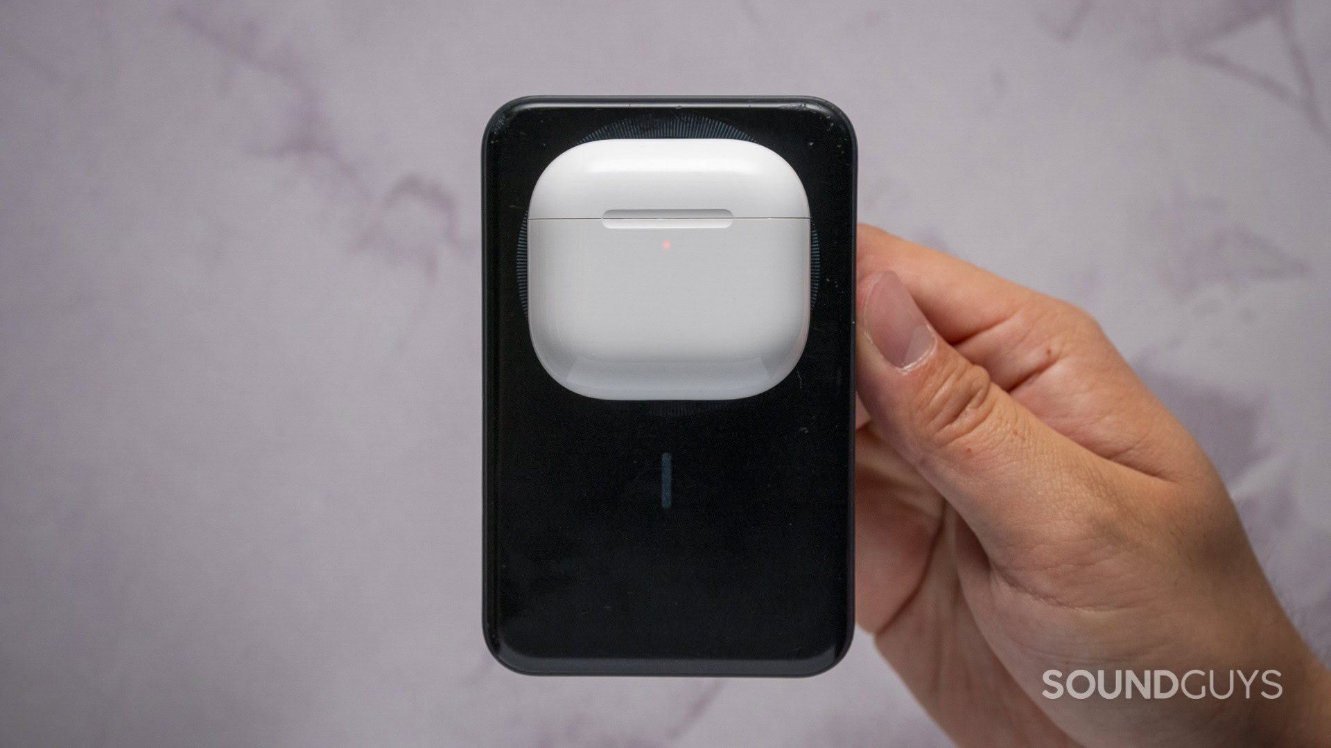 Apple AirPods 5 and Apple AirPods 5 with Wireless Charging-07 White AirPods charging case resting on the back of a smartphone for wireless charging.