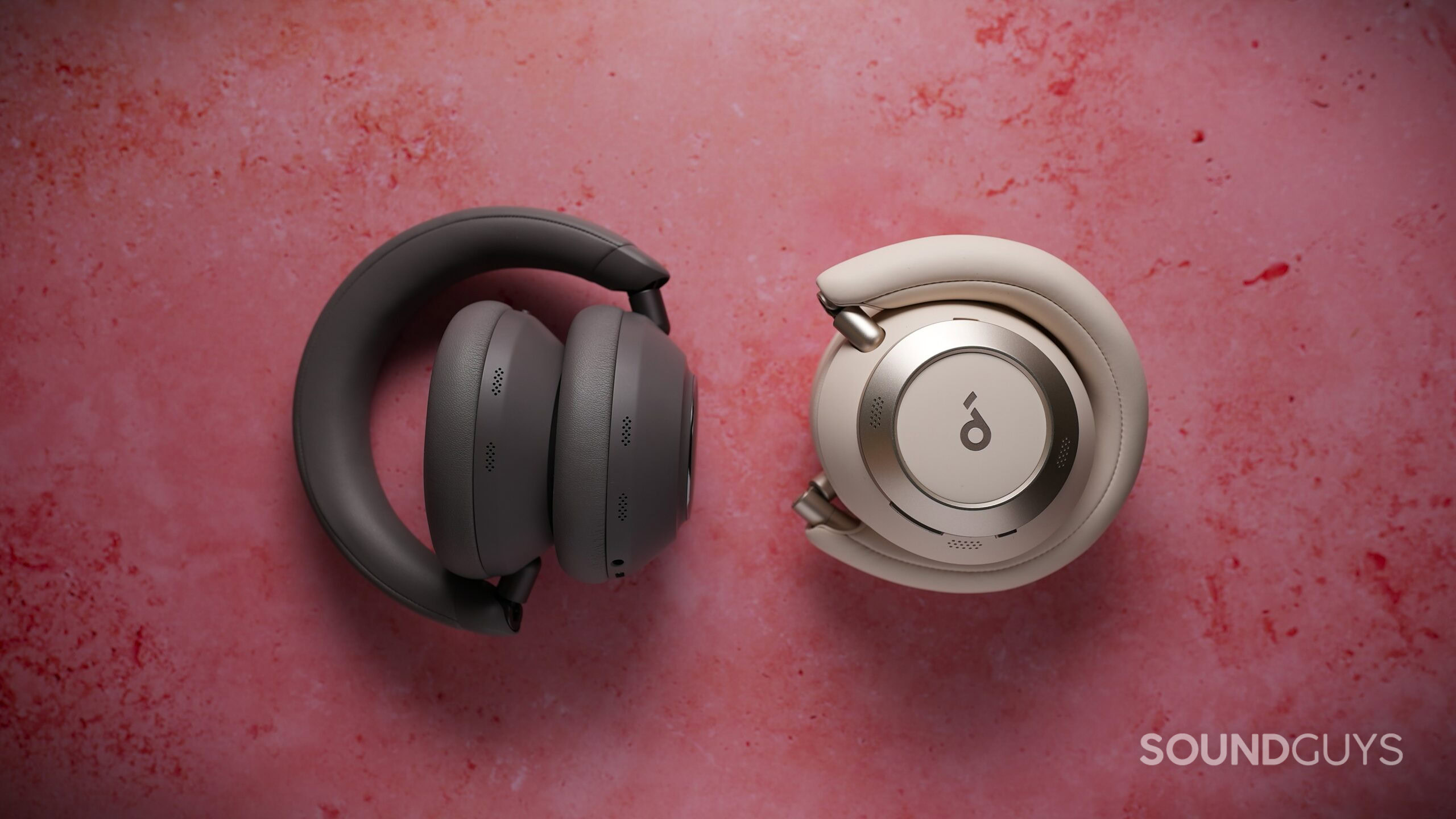 soundcore space 2 pro folded compared to space one pro Folded gray Soundcore Space 2 Pro headphones beside folded white Space One Pro headphones on a pink surface.