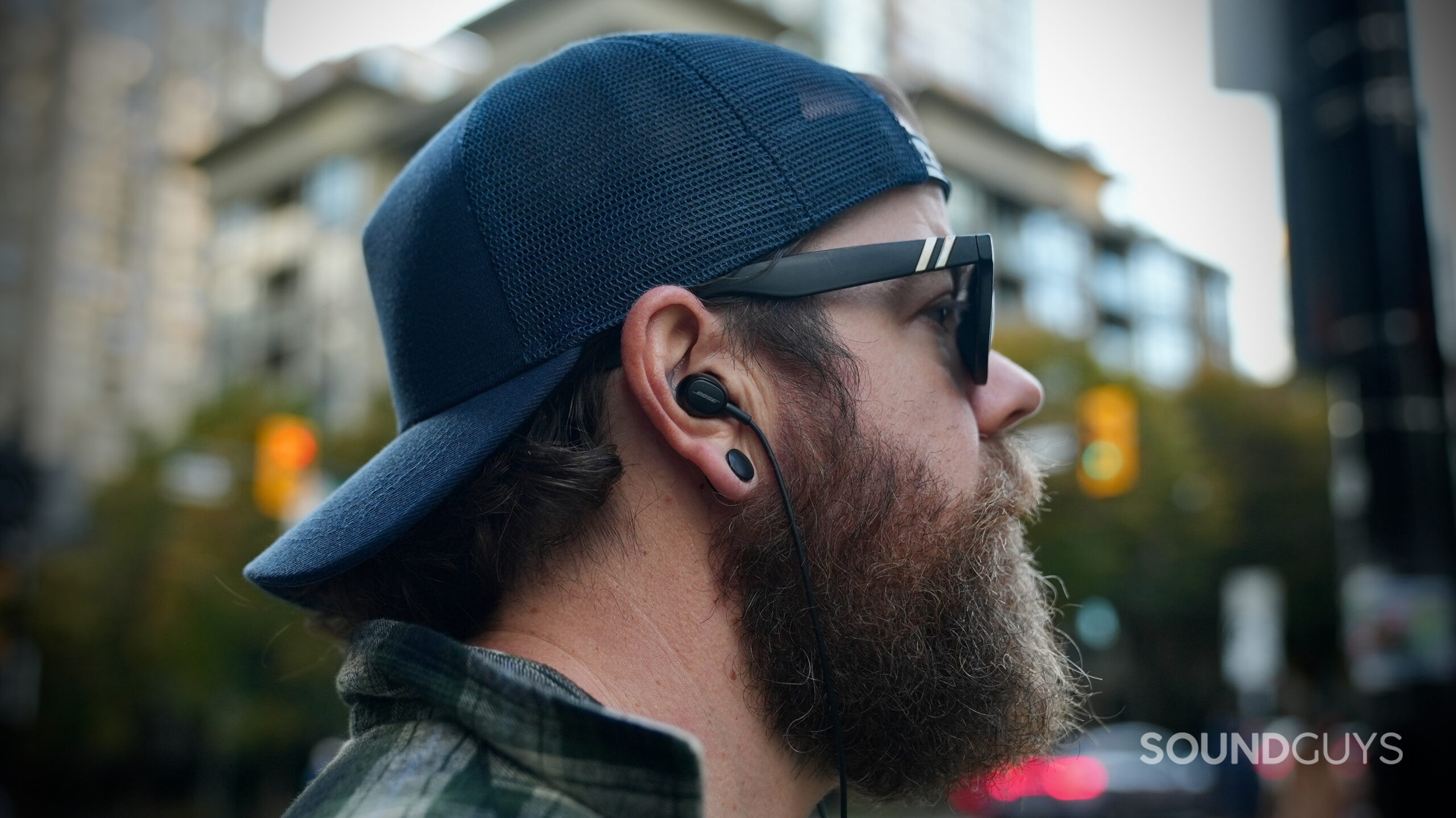 Bose Noise Canceling Wired Earbuds - 1 Side view of a person wearing Bose wired earbuds outdoors.