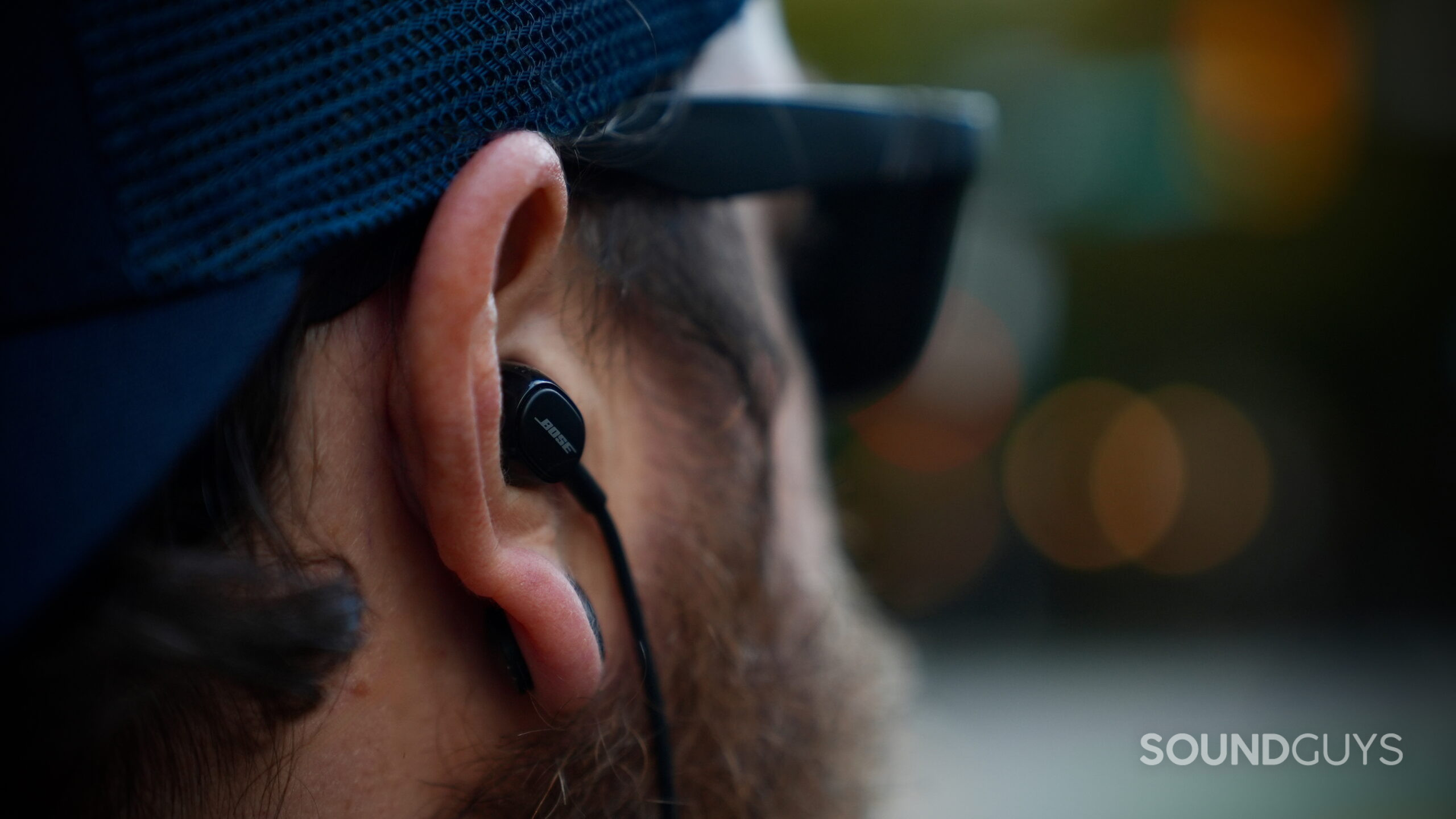 Bose Noise Canceling Wired Earbuds - 2 Close-up of a person wearing a Bose wired earbud with the cable running behind the ear.