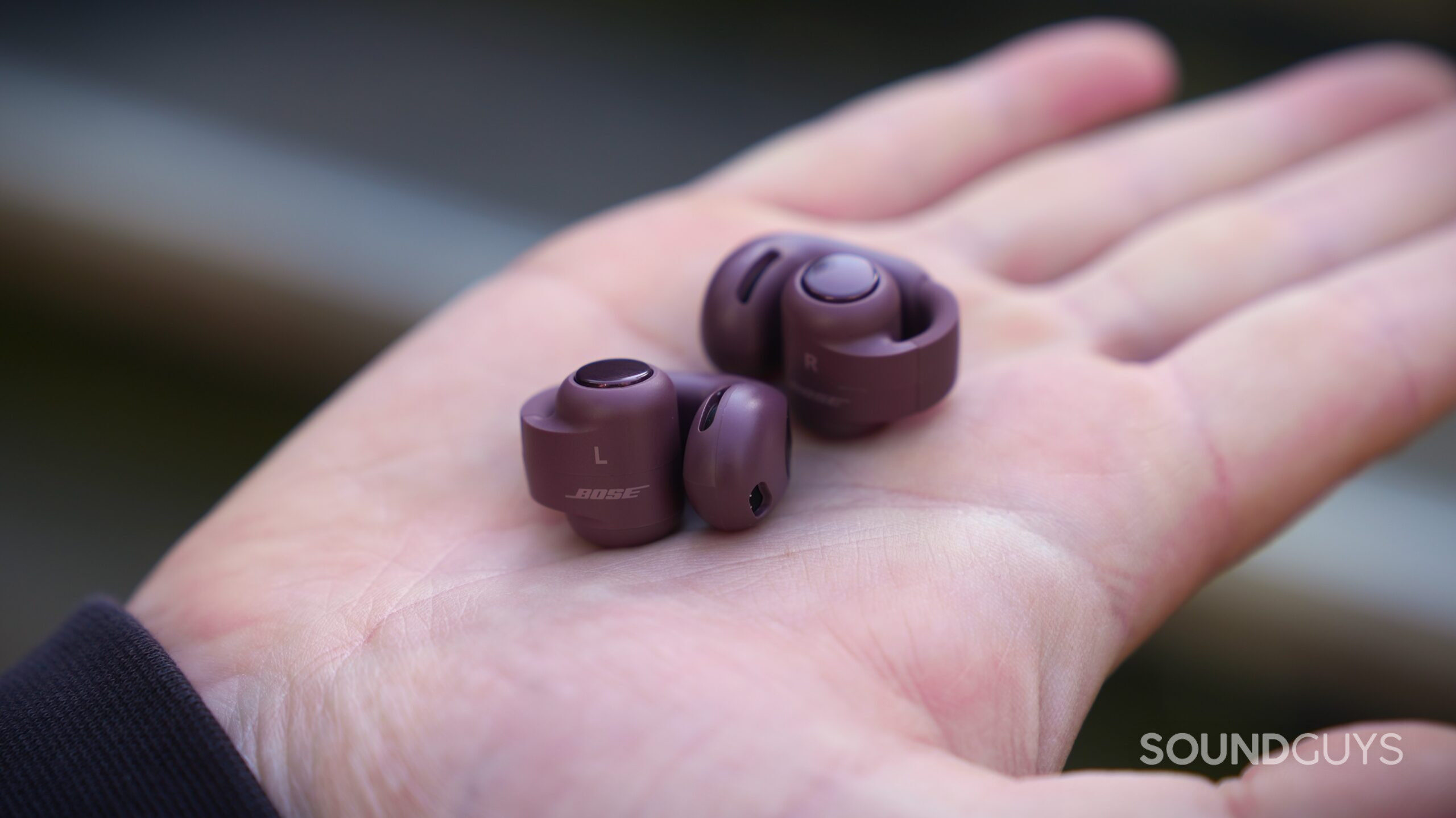 DSC09923 Cherry Chocolate Bose Ultra Open 2 earbuds resting in an open palm, showing their left and right markings, control buttons, and flexible loops.