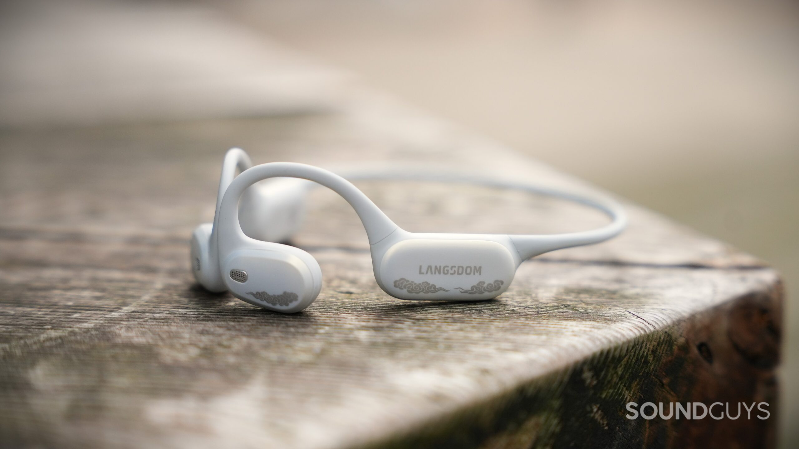 airwave pro 2 hero 2 White Langsdom AirWave Pro 2 open-ear headphones resting on a wooden surface.
