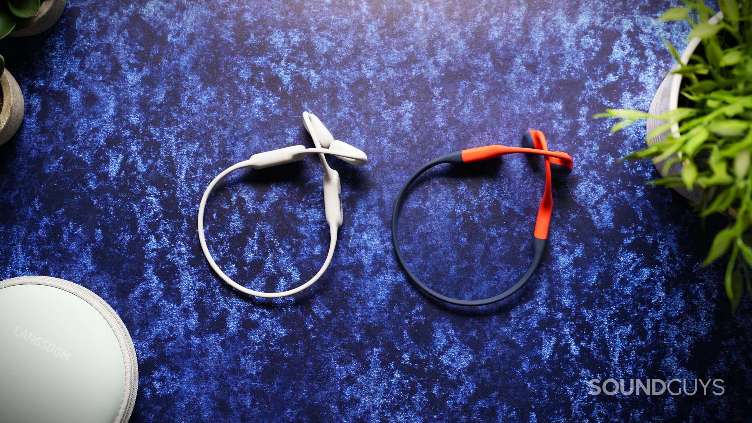 airwave pro 2 vs shokz bone conduction White Langsdom AirWave Pro 2 headphones beside black and orange Shokz bone-conduction headphones.